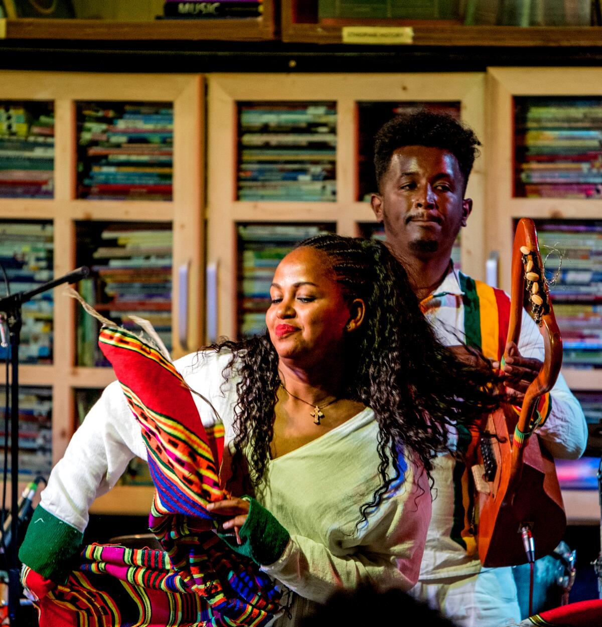 A woman dances while a man plays an instrument behind her.