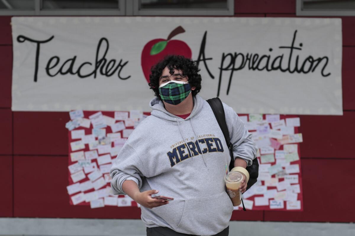A person stands in front of a sign that says "Teacher Appreciation"