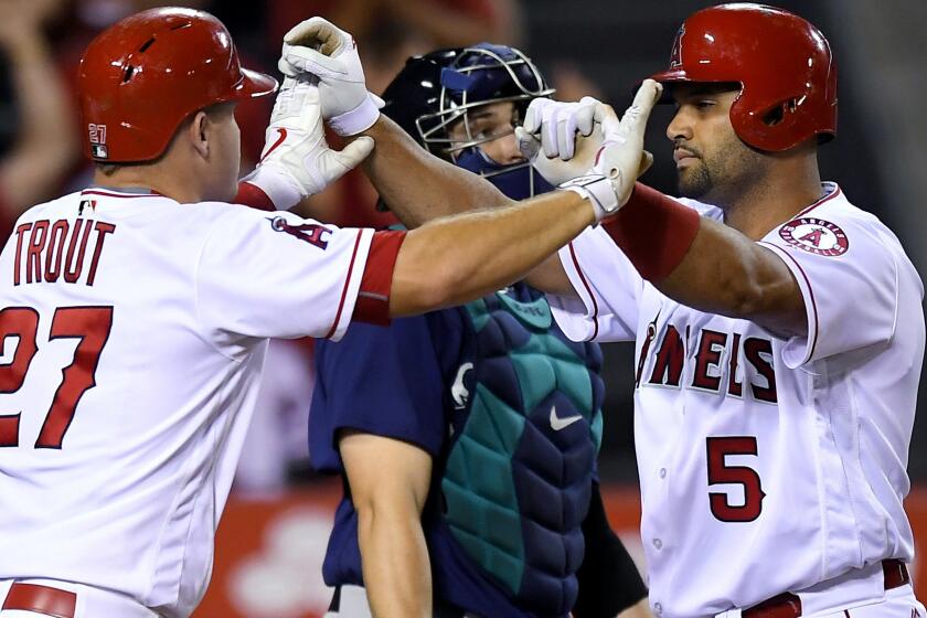 Angels designated hitter Albert Pujols is congratulated by teammate Mike Trout after hitting a three-run home run against the Mariners.