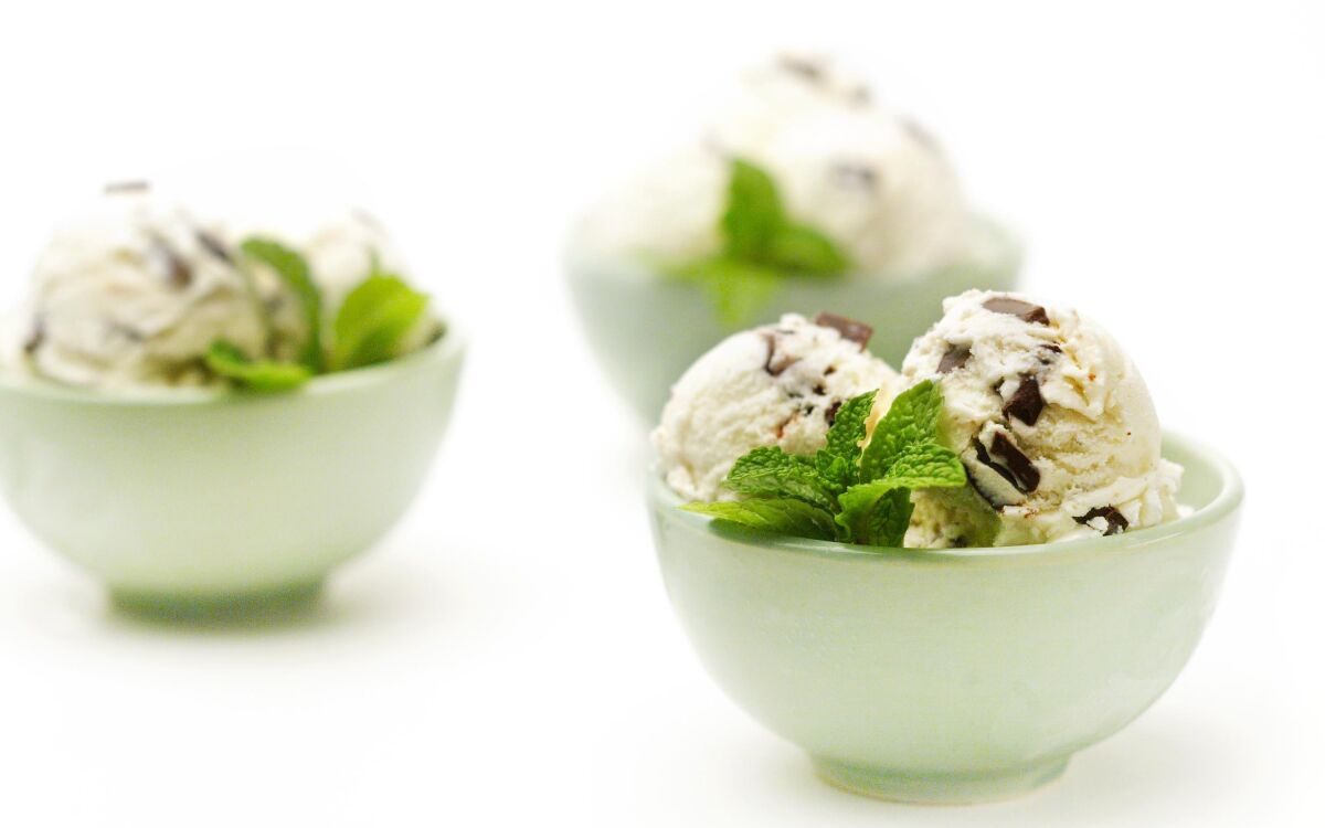 Three small bowls of chocolate mint ice cream garnished with fresh mint leaves.