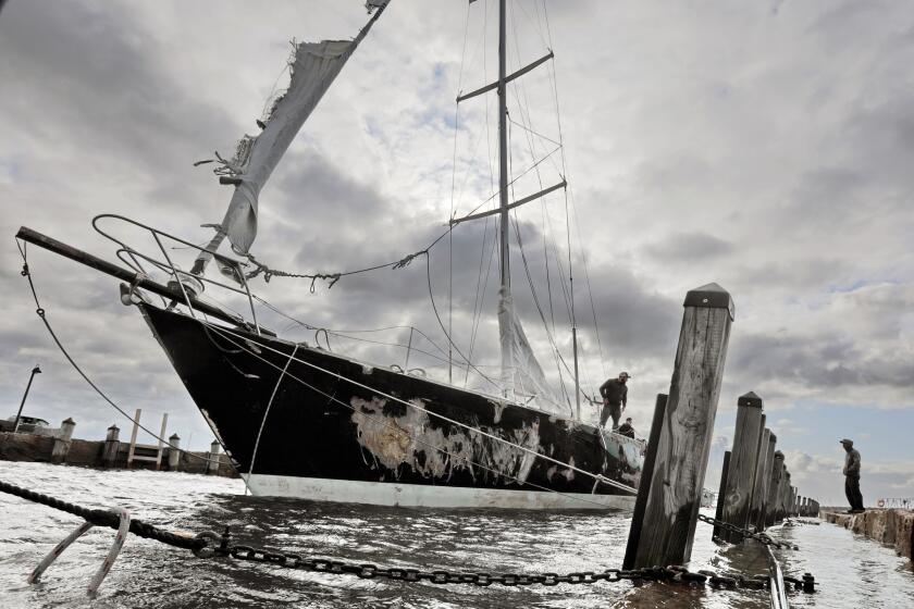 Concerned residents try to stabilize the 55-foot sailboat Fearless, which was damaged after it washed into a wharf in Mattapoisett harbor due to strong overnight winds, Thursday morning, Oct. 17, 2019, in Mattapoisett, Mass. ( Peter Pereira/Standard Times via AP)