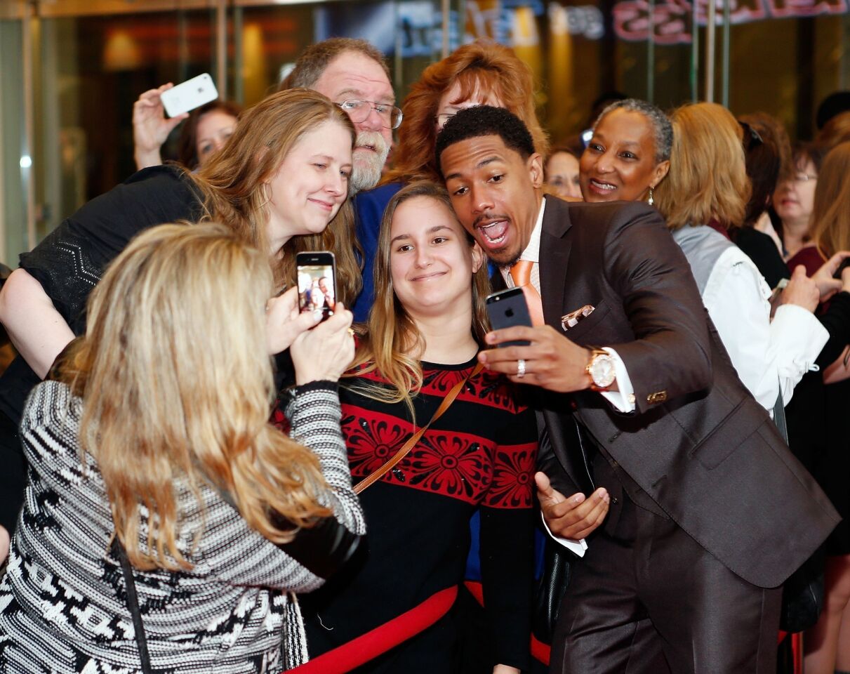 Model and media personality Nick Cannon takes selfies with fans at the "America's Got Talent" red carpet event at Madison Square Garden on April 4, 2014, in New York City.