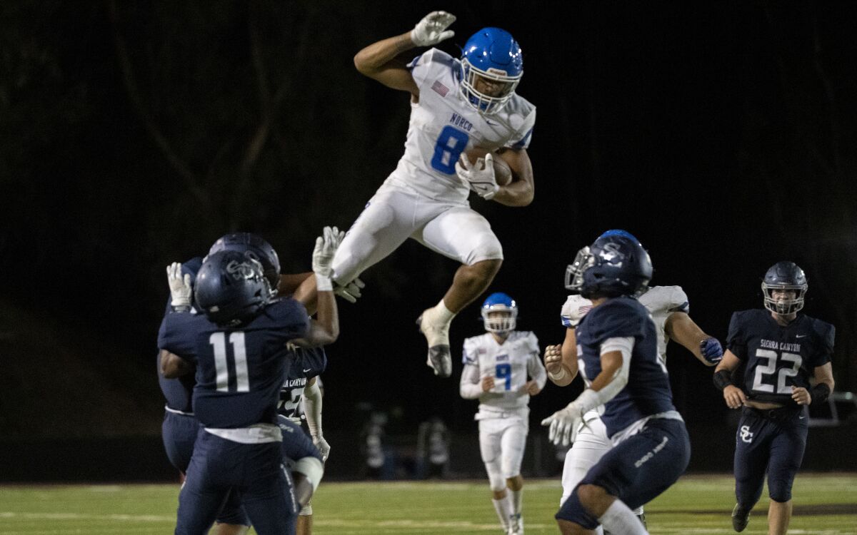  Norco running back Jaydn Ott tries to leap over Sierra Canyon defenders.