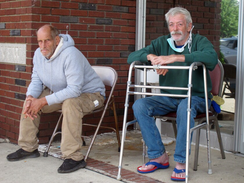 Richard Leoncini, left, and Wayne Krause, right, sit outside a temporary evacuation center in Manville, N.J., on Friday, Sept. 3, 2021. Like many in their neighborhood near the flood-swollen Raritan River, they had to be rescued by boat in the middle of the night as flood waters surged into their apartments. (AP Photo/Wayne Parry)