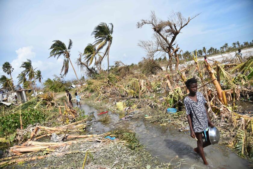A girl walks past debris left by Hurricane Matthew in Sous Roche, Les Cayes, in the southwest of Haiti, on Oct. 9, 2016. H
