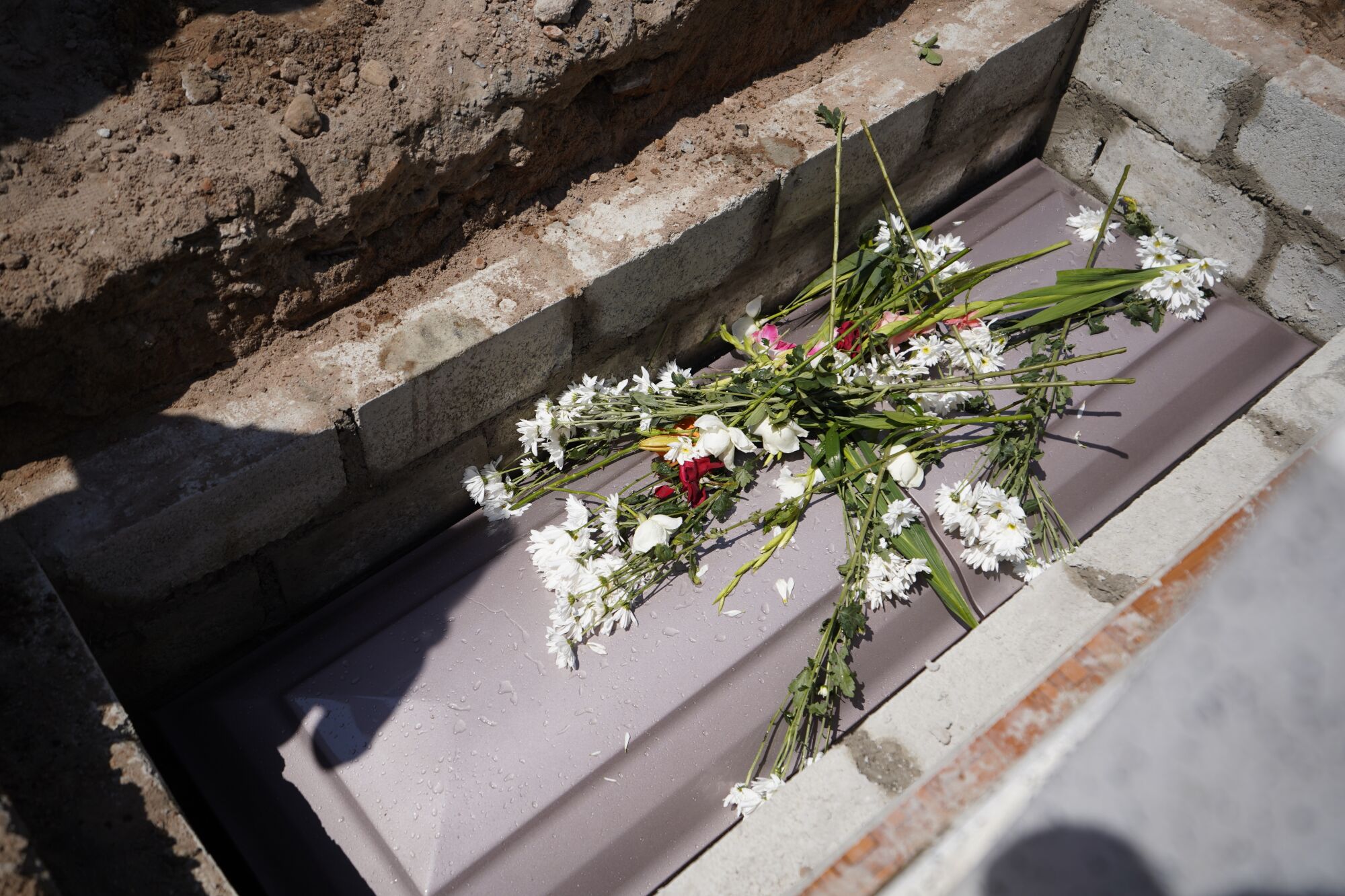 Familiares echan flores sobre la tumba de María Eugenia Chávez Segovia.