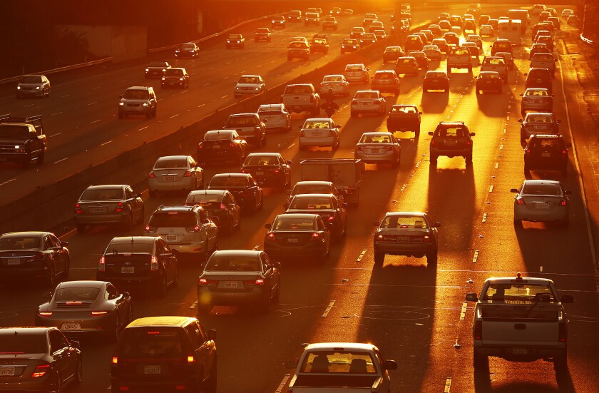Morning traffic bathed in the orange glow of sunrise crawls across the many lanes of the 101 Freeway