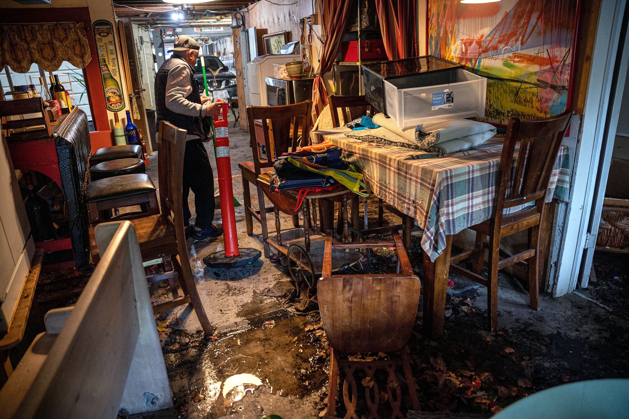 A man moves furniture as flood waters enter a San Francisco home.