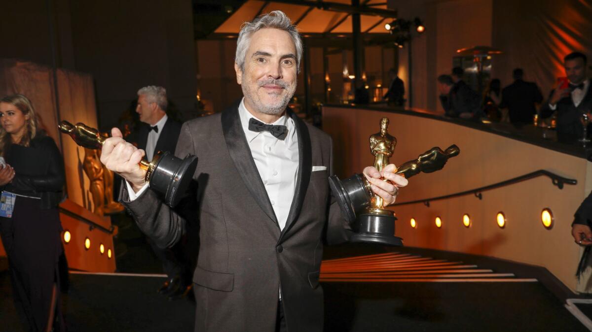 Alfonso Cuarón juggles his Oscars for director, foreign-language film and cinematography for "Roma."