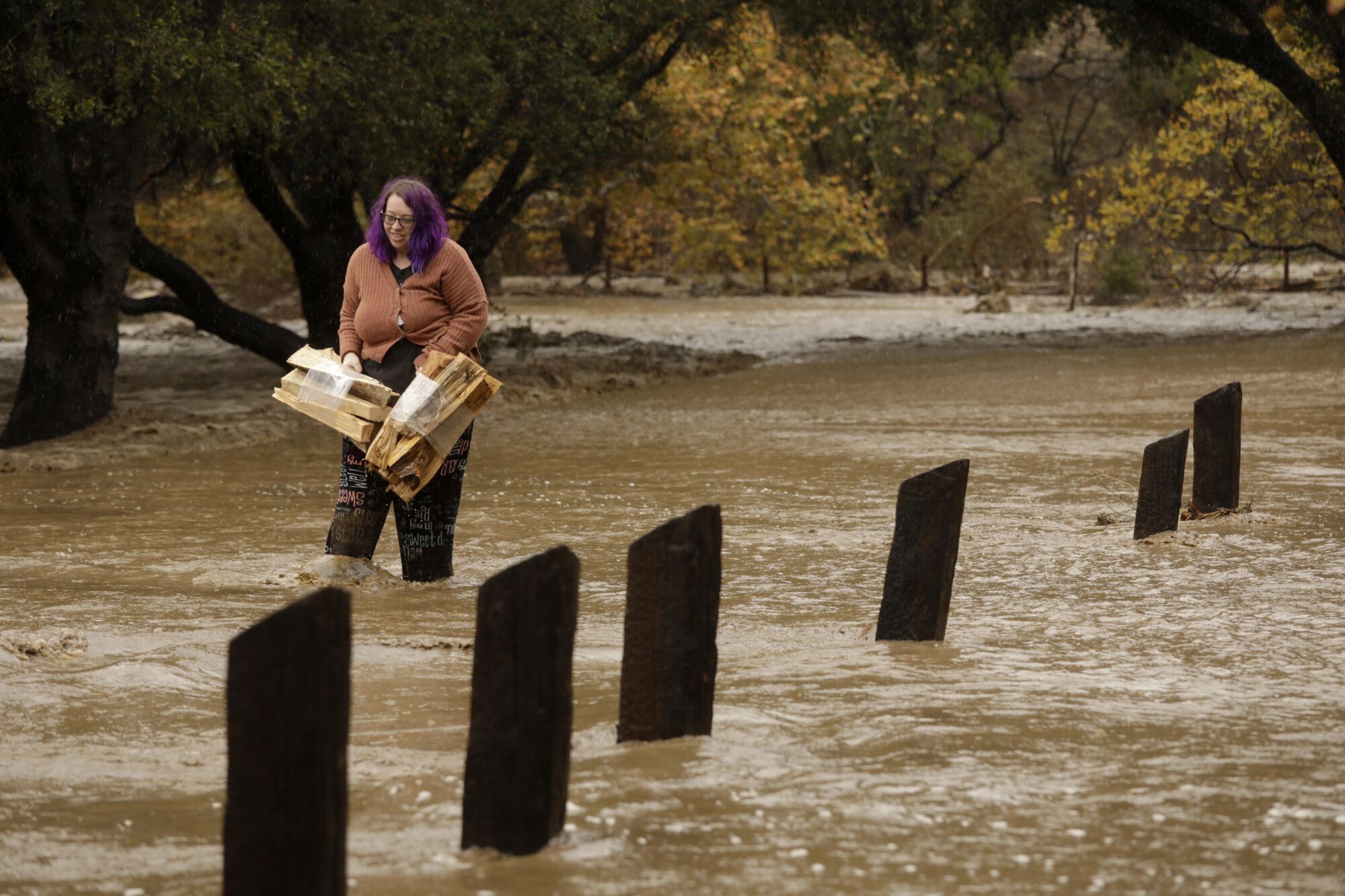 Ashley Ward carries fire wood from her campsite that was flooded by a creek that overflowed into the area 