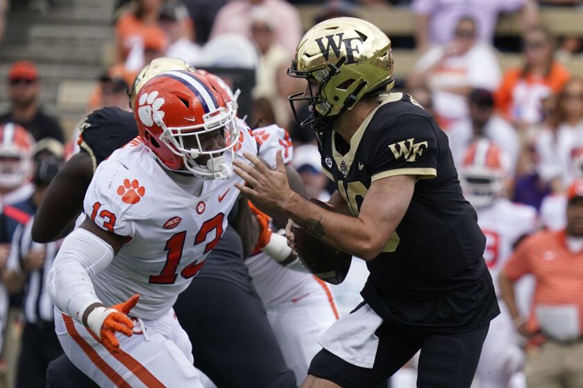 Wake Forest quarterback Sam Hartman (10) looks to pass as Clemson defensive tackle Tyler Davis (13) defends during the first half of an NCAA college football game in Winston-Salem, N.C., Saturday, Sept. 24, 2022. (AP Photo/Chuck Burton)