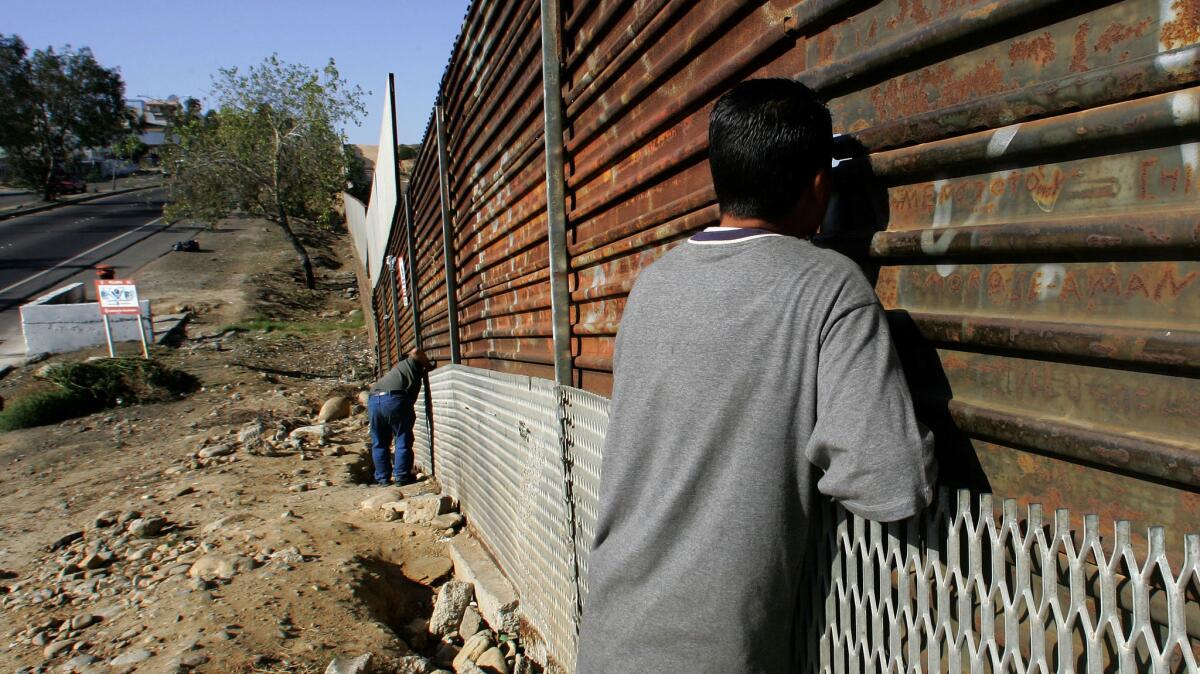 Mexican citizens look through the border between the U.S. and Tijuana in this 2006 file photo. On Friday, a federal appeals court refused to put a hold on a decision to temporarily block President Trump’s order to limit asylum only to those who cross at official points of entry.