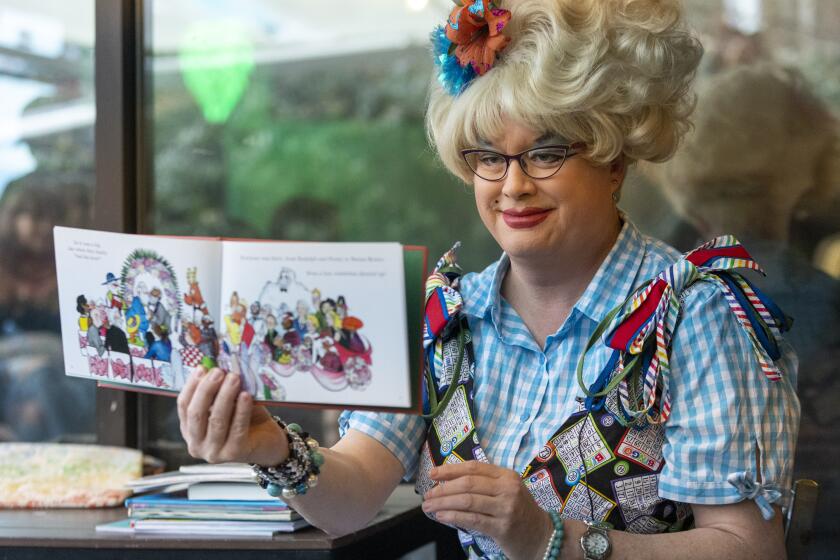 Drag Queen, Sylvia O'Stayformre, holds up the book "Santa's Husband" as she reads to kids and parents during Drag Queen Storytime at Brewmaster's Tap Room in Renton, Wash. on Saturday, Jan. 14, 2023.