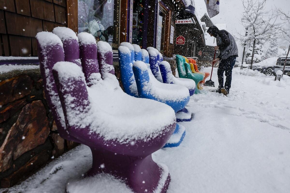 Tyler Reid tidies up the entrance to a candy shop in downtown as a snowstorm blankets Big Bear. 