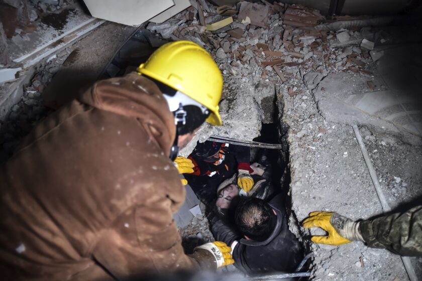 Emergency workers and medics rescue a woman out of the debris of a collapsed building in Elbistan, Kahramanmaras, in southern Turkey, Tuesday, Feb. 7, 2023. Rescuers raced Tuesday to find survivors in the rubble of thousands of buildings brought down by a 7.8 magnitude earthquake and multiple aftershocks that struck eastern Turkey and neighboring Syria. (Ismail Coskun/IHA via AP)