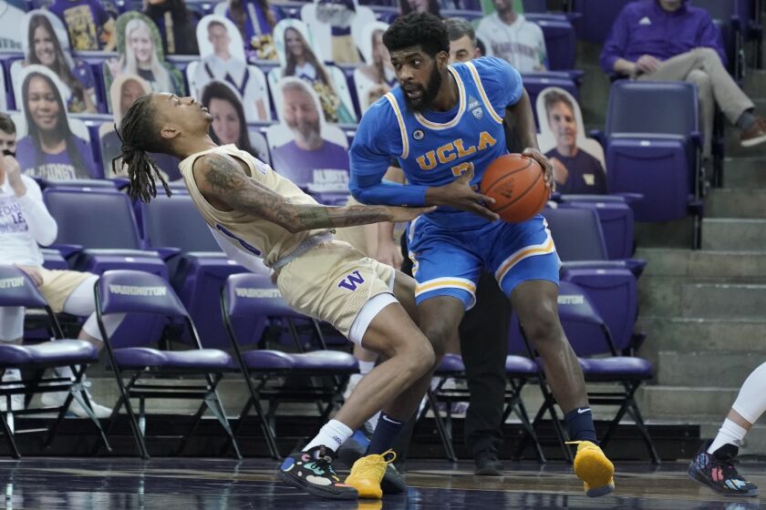 CORRECTS WASHINGTON PLAYER TO HAMEIR WRIGHT, INSTEAD OF NATE ROBERTS - UCLA forward Cody Riley, right, collides with Washington forward Hameir Wright, left, during the first half of an NCAA college basketball game, Saturday, Feb. 13, 2021, in Seattle. (AP Photo/Ted S. Warren)