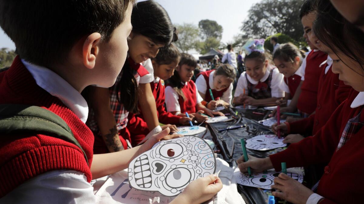 Students from St. Anthony School color face masks at a workshop at Calvary Cemetery in East Los Angeles to teach youngsters about Dia de los Muertos.