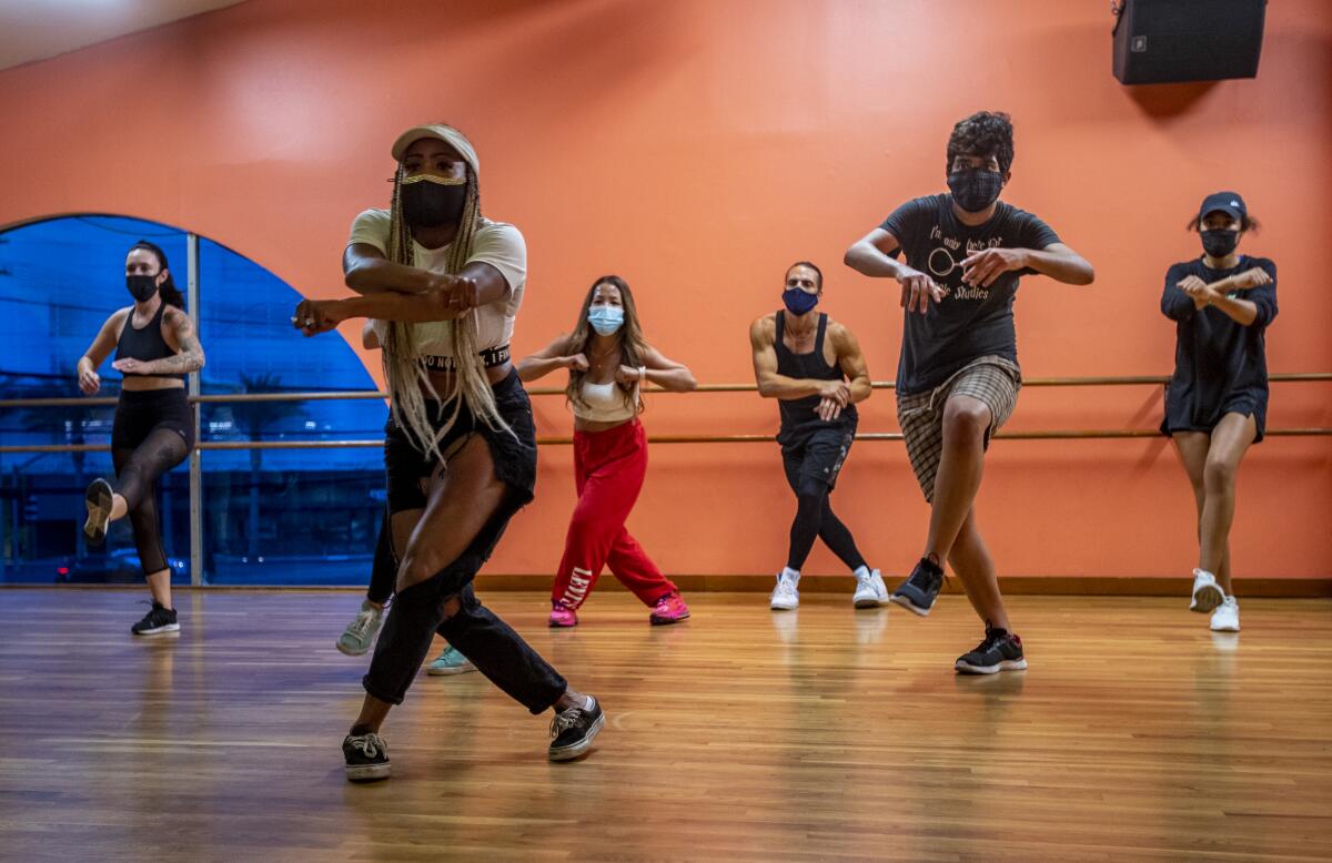 A dance instructor leads teaches students hip-hop movies inside a dance studio.