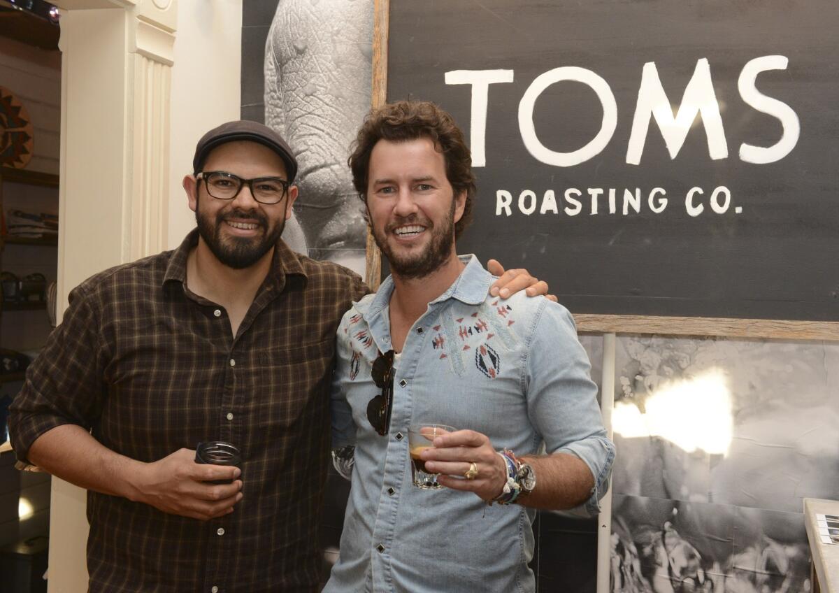 The maker of Toms shoes is expanding into coffee, the company said Tuesday. Above, Toms founder Blake Mycoskie, right, attends the opening of a store in Austin, Texas with master coffee roaster Angel Orozco, who is part of the expansion.