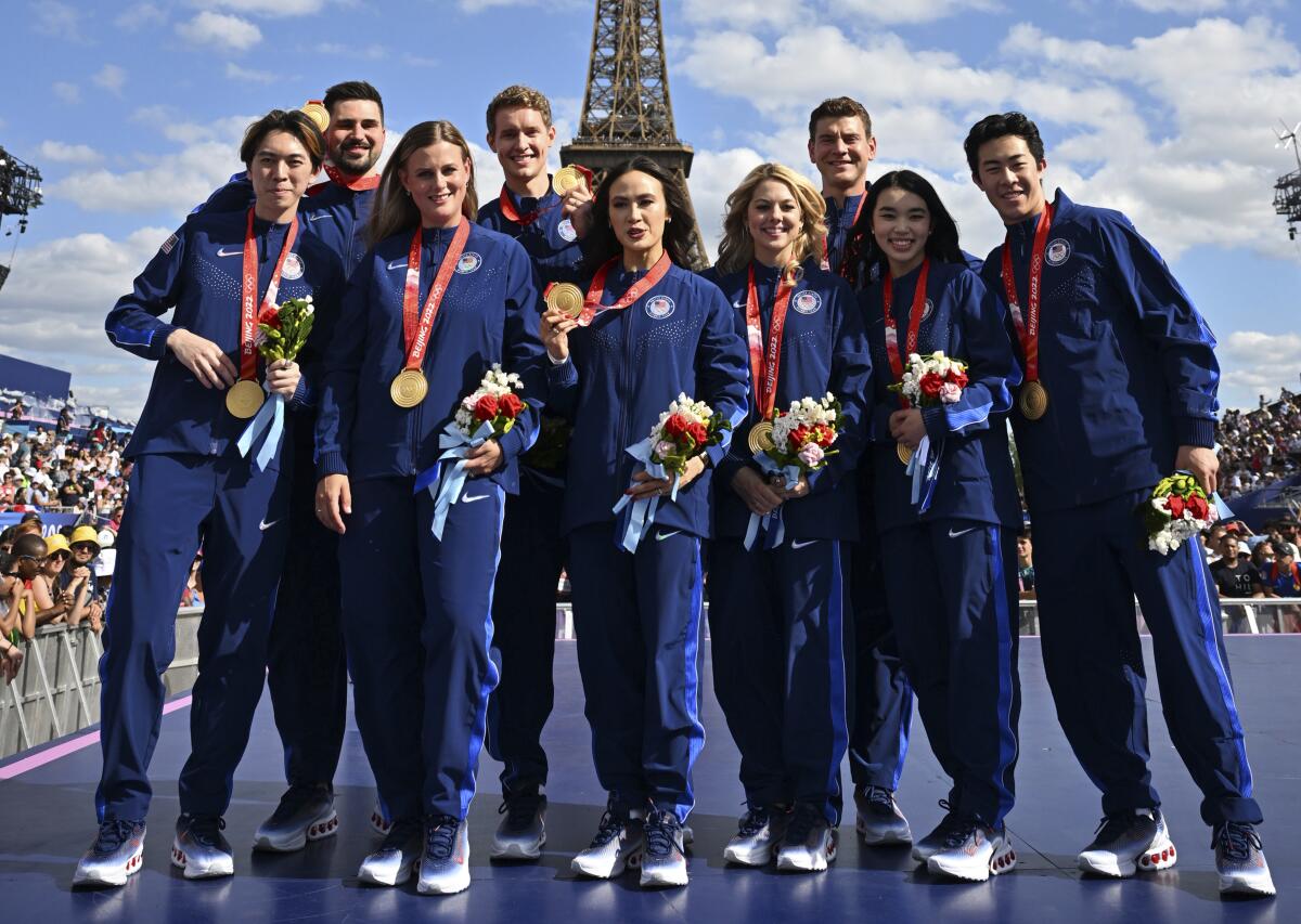 U.S. figure skaters pose against a backdrop of the Eiffel Tower during a ceremony Wednesday to reallocate the medals 