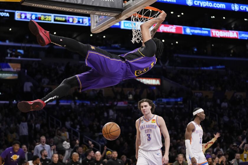 Los Angeles Lakers forward Anthony Davis, top, dunks as Oklahoma City Thunder guard Josh Giddey, lower left, and guard Shai Gilgeous-Alexander look on during the first half of an NBA basketball game Friday, March 24, 2023, in Los Angeles. (AP Photo/Mark J. Terrill)