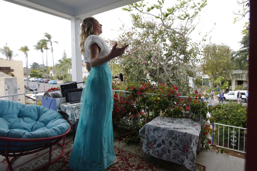 Opera singer Victoria Robertson, a soprano, sings from the porch of her North Park home on April 19, 2020. For the second week in a row, Robertson performed for 15 minutes to a crowd, who kept their distance from each other on the street below.