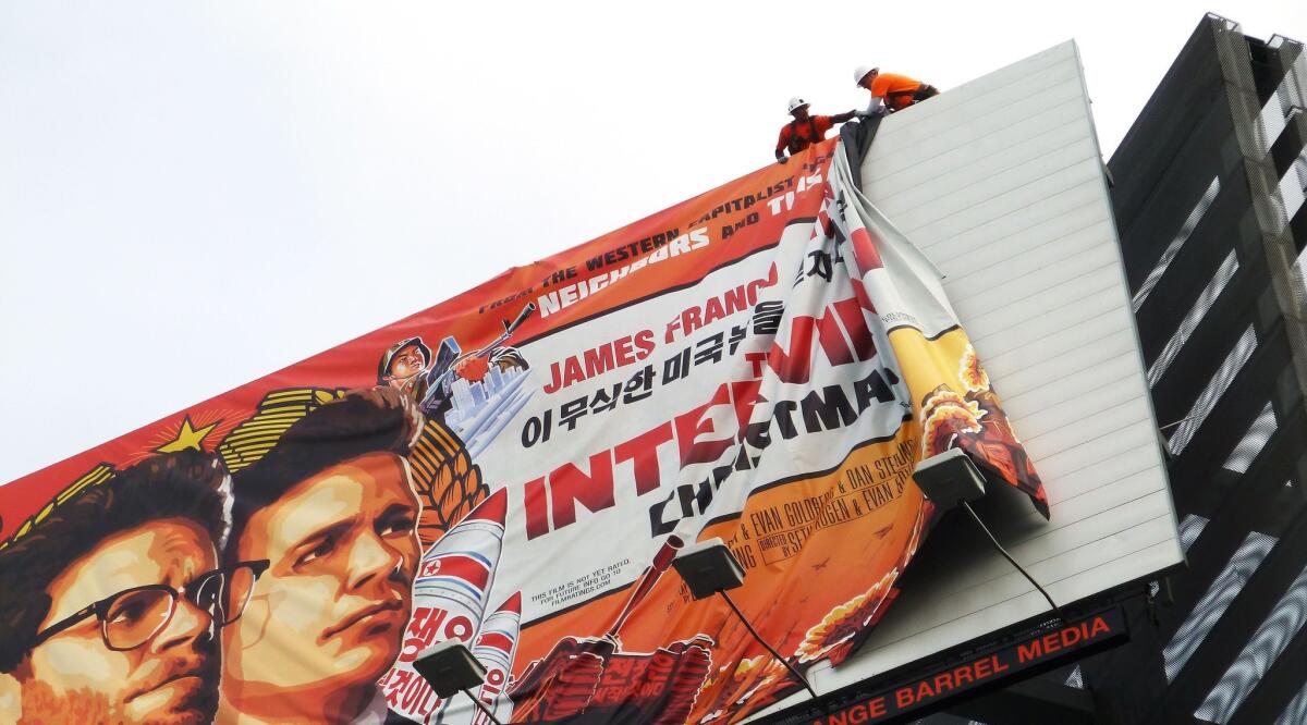 Workers remove a billboard ad for "The Interview" in Hollywood on Thursday, a day after Sony announced it was canceling the movie's Christmas release due to a threat from a group of hackers that U.S. investigators have linked to North Korea.