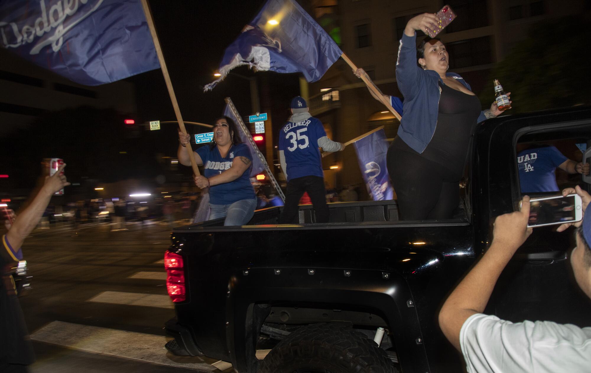 Fans wave Dodgers flags from the back of a pickup truck.