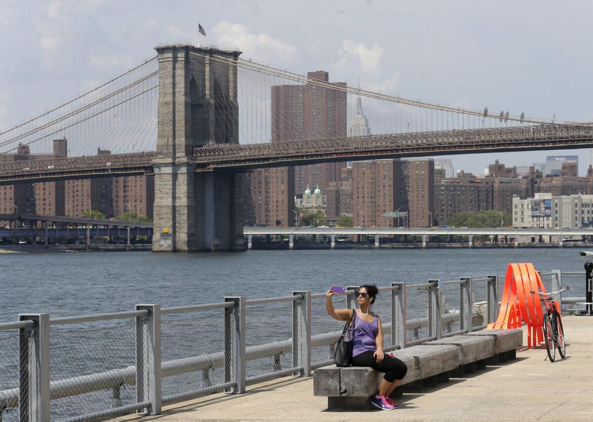 epa04864194 A woman takes a selfie along the East River in Brooklyn Bridge Park in Brooklyn, New York, USA, 28 July 2015. Temperatures reached 91F (33C) and are expected to remain in the 90's tomorrow EPA/ANDREW GOMBERT ** Usable by LA, CT and MoD ONLY **