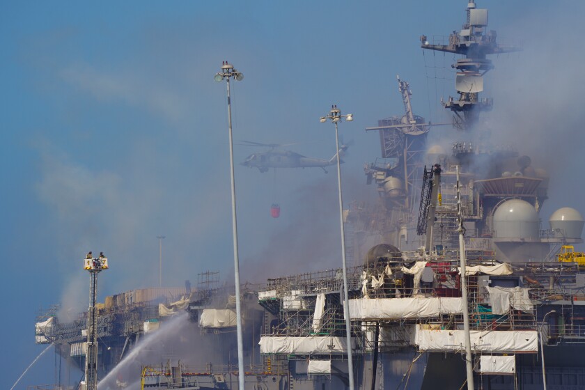 Helicopters conduct water drops over the fire that continues to burn aboard the Bonhomme Richard. 
