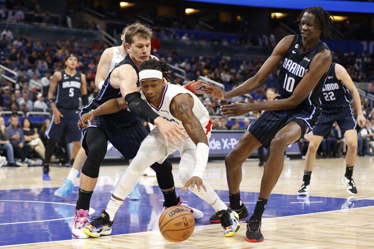 Clippers guard Terance Mann reaches for a the ball while under pressure from Orlando Magic centers Moritz Wagner and Bol Bol.