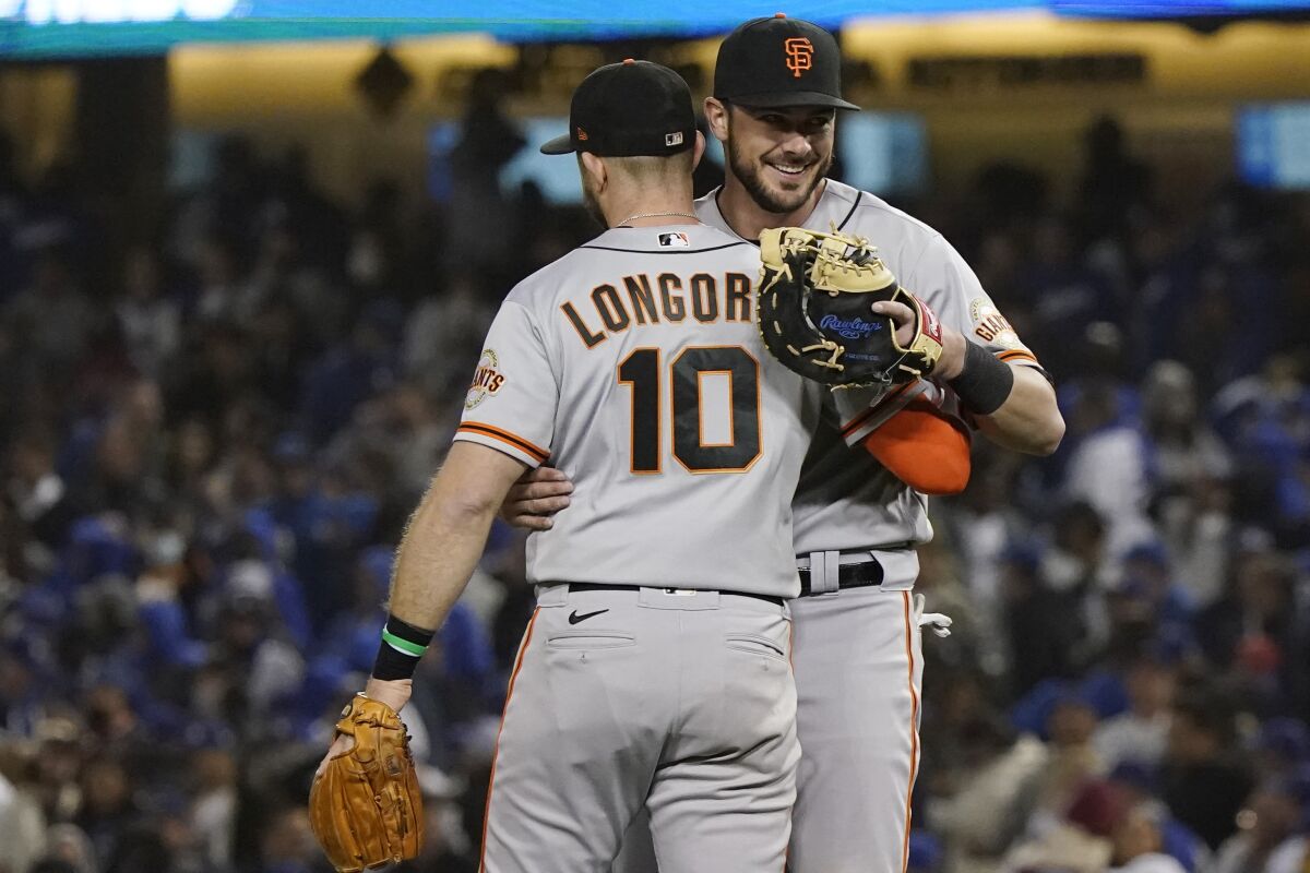 San Francisco Giants' Evan Longoria (10) hugs teammate Kris Bryant, right, after Longoria's solo home run gave the the Giants a 1-0 win over the Los Angeles Dodgers in Game 3 of a baseball National League Division Series, Monday, Oct. 11, 2021, in Los Angeles. (AP Photo/Marcio Sanchez)