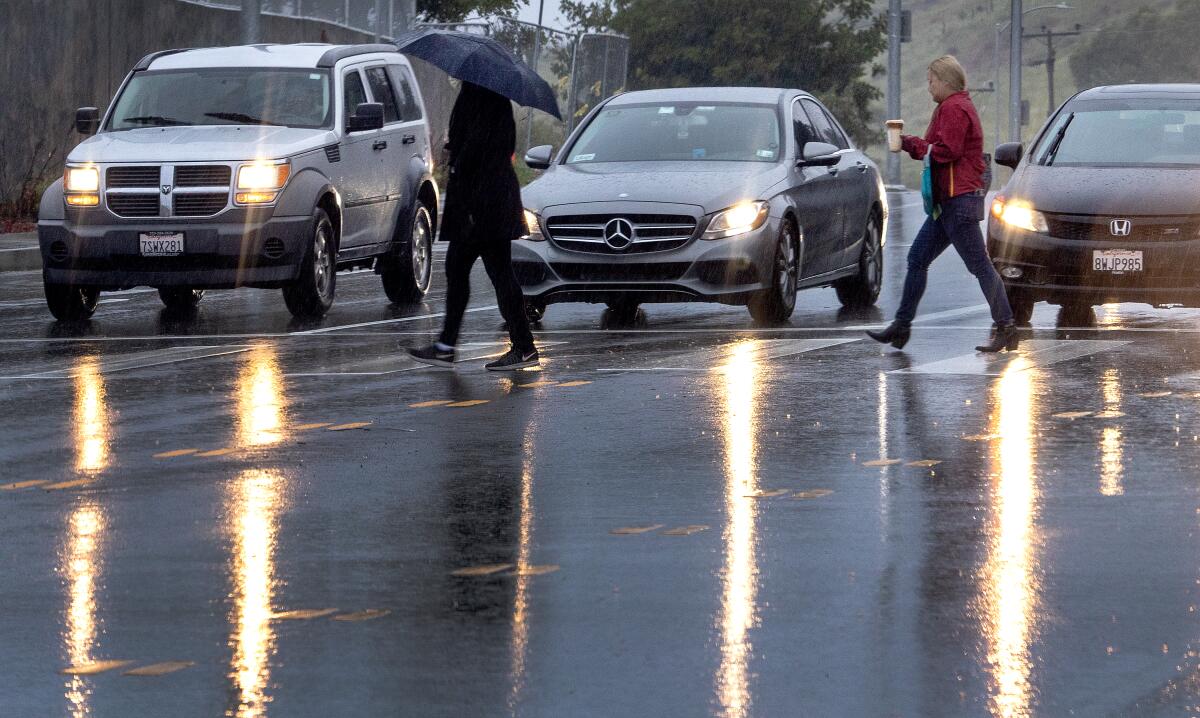 Pedestrians cross the road in the rain in El Sereno on March 21.