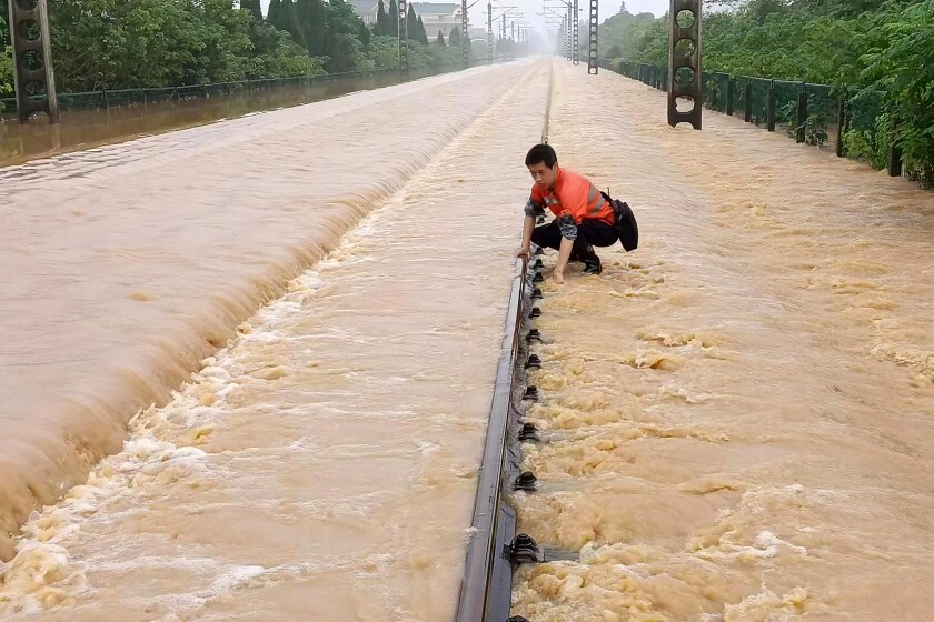 A worker checks a section of flooded railway
