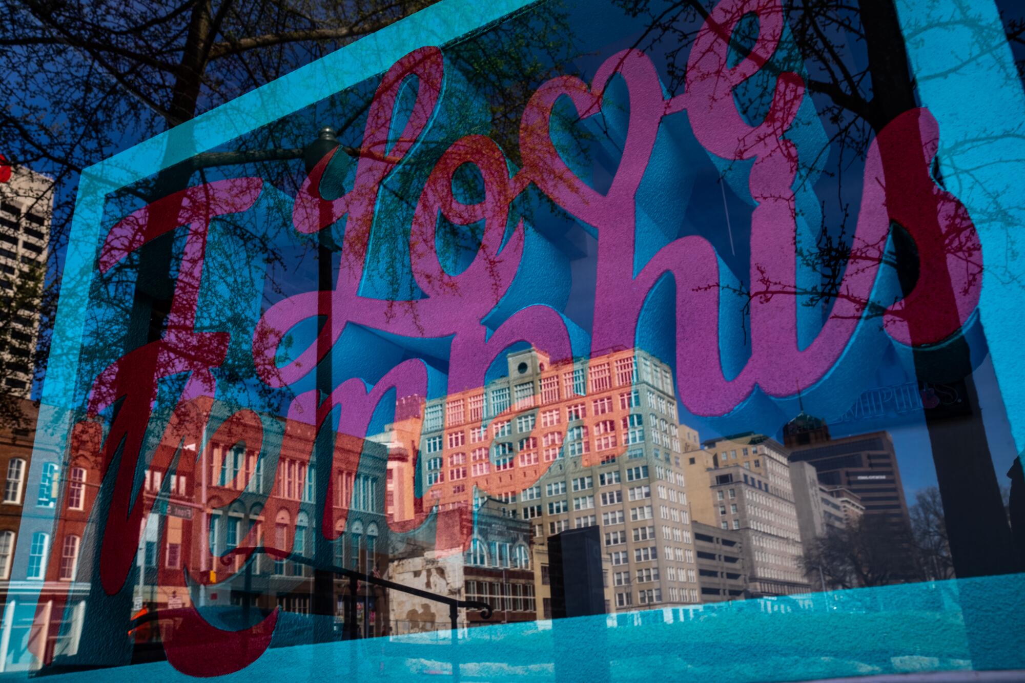 Buildings are reflected in a window with a sign that says "I Love Memphis."