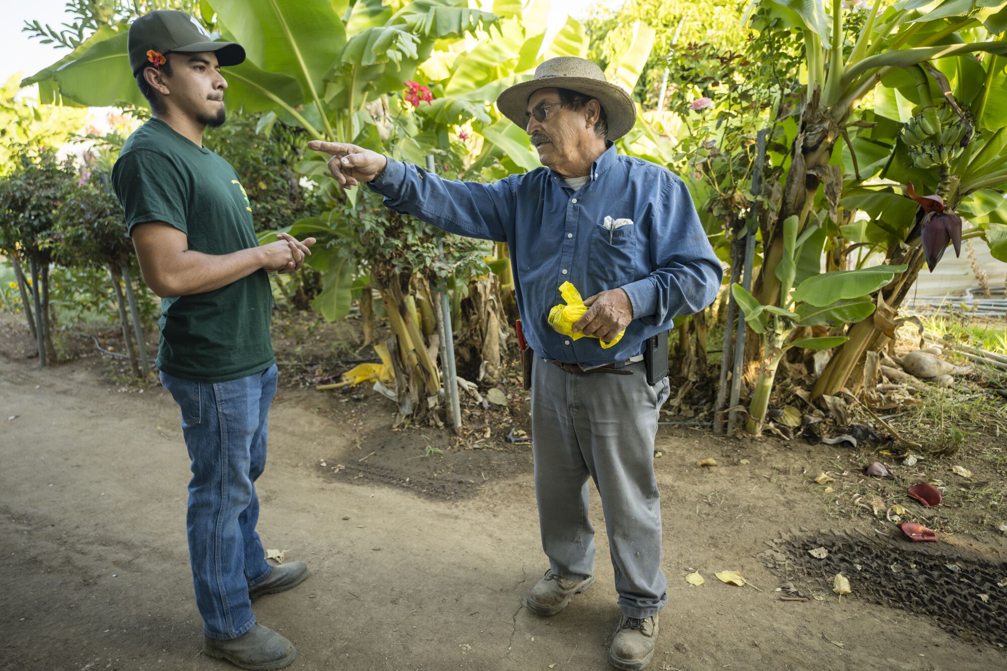 An older man talks to a younger man outdoors.