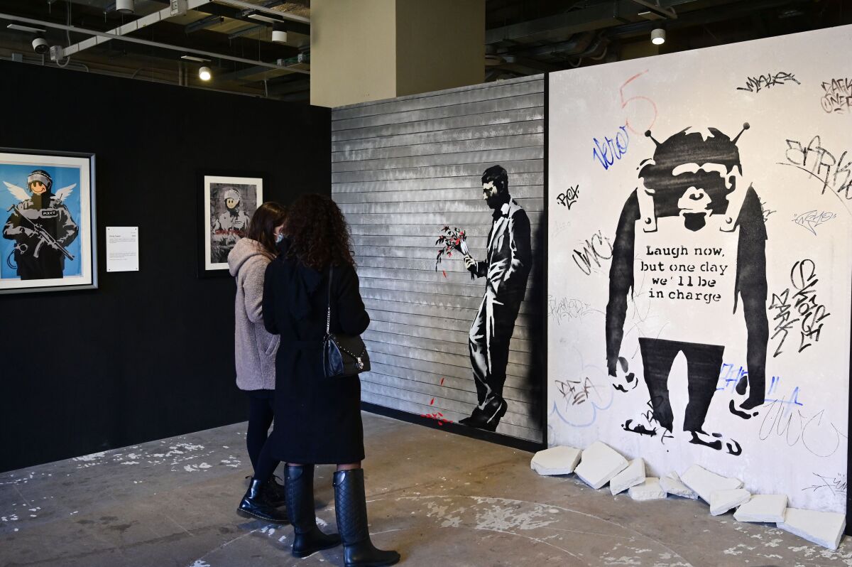 Visitors look at paintings by British street artist Banksy during an exhibition in Milan, Italy in December 2021.