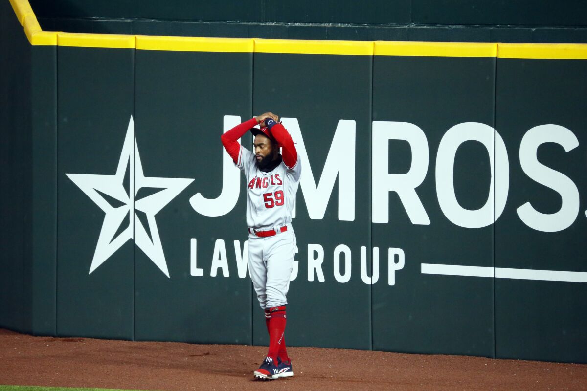 The Angels' Jo Adell puts his hands on his head after a fly ball by Texas Rangers' Nick Solak popped out of his glove.