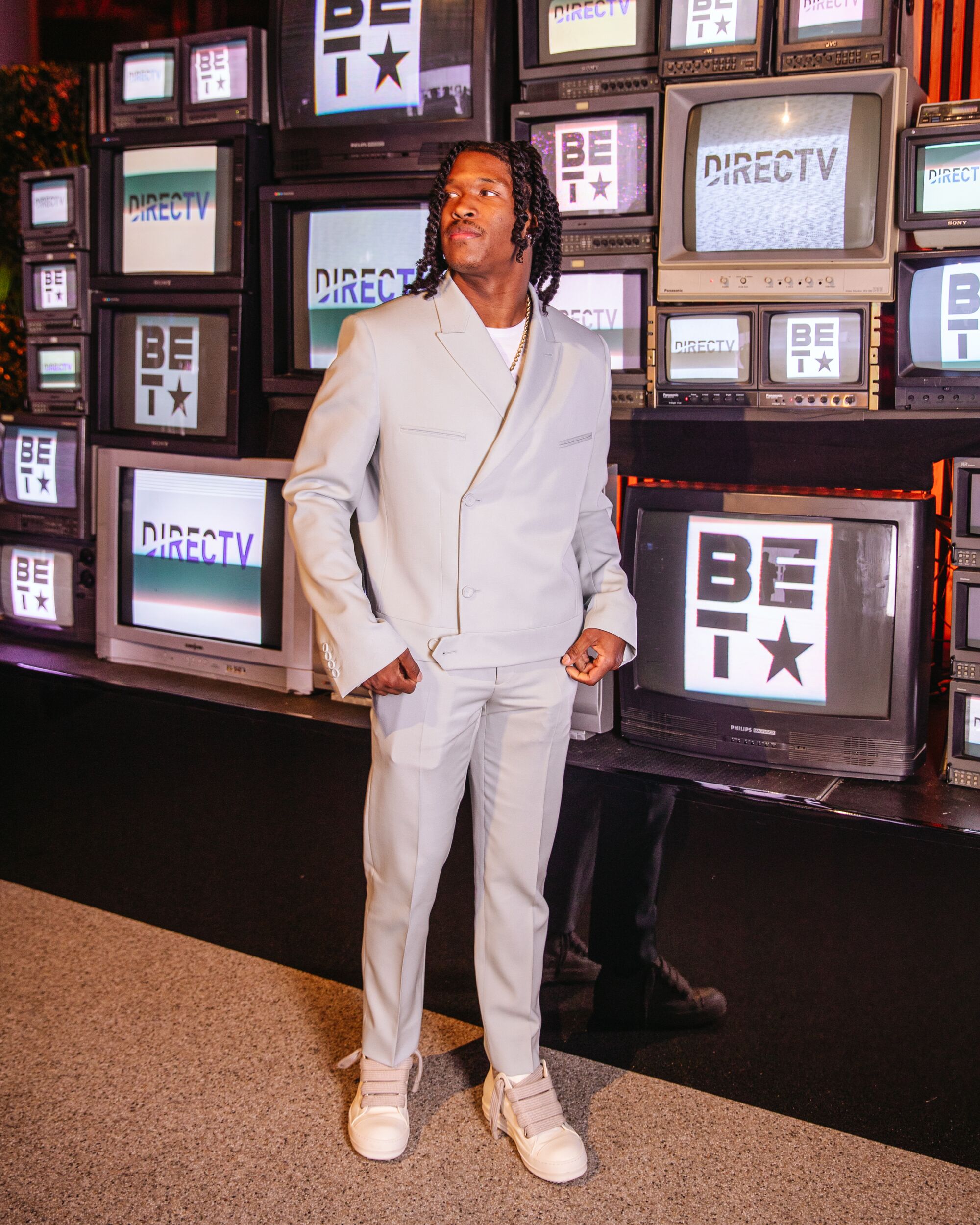 A man poses for a portrait in front of a bank of TV sets.