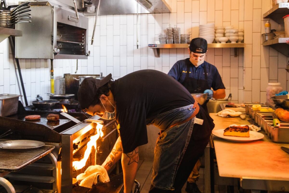 Derek Harris, supervisor, and Trace Kopcha, line cook, cook food in the kitchen of Little Frenchie in Coronado.