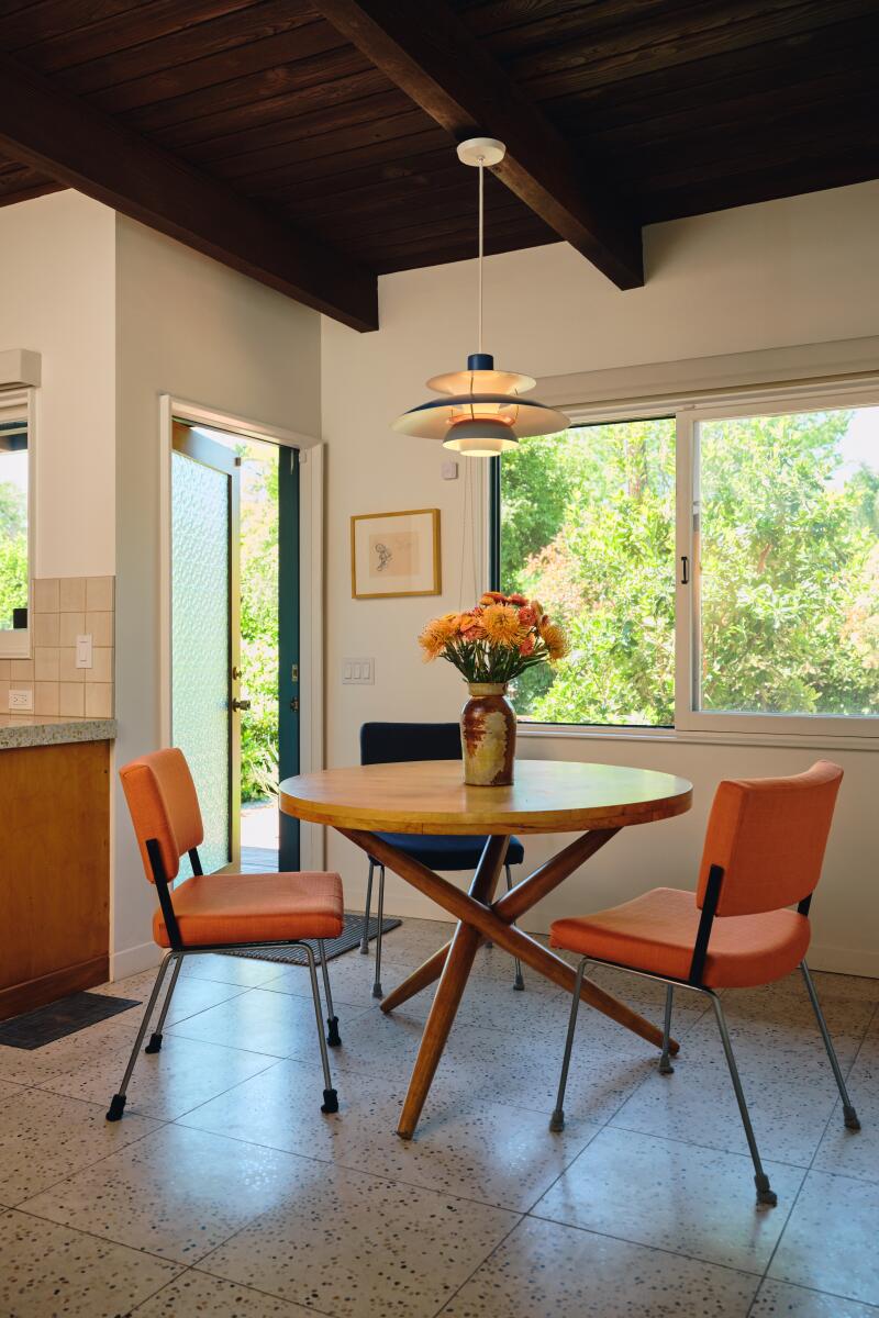 Two vinyl orange chairs around a round table topped by a pendant light.