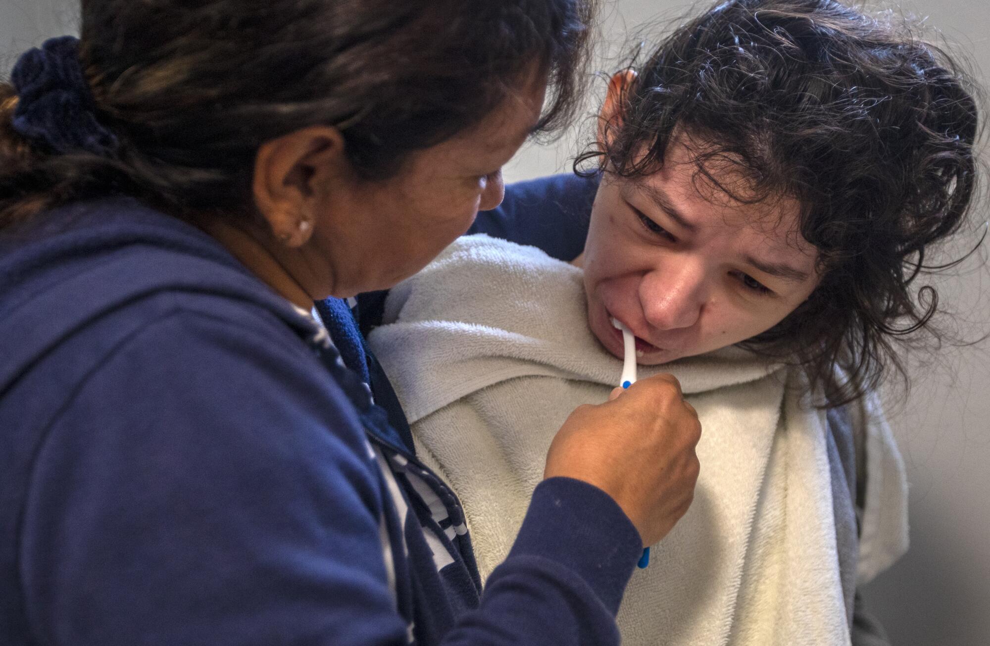 Rosa Andresen, left, brushes her  daughter's teeth.