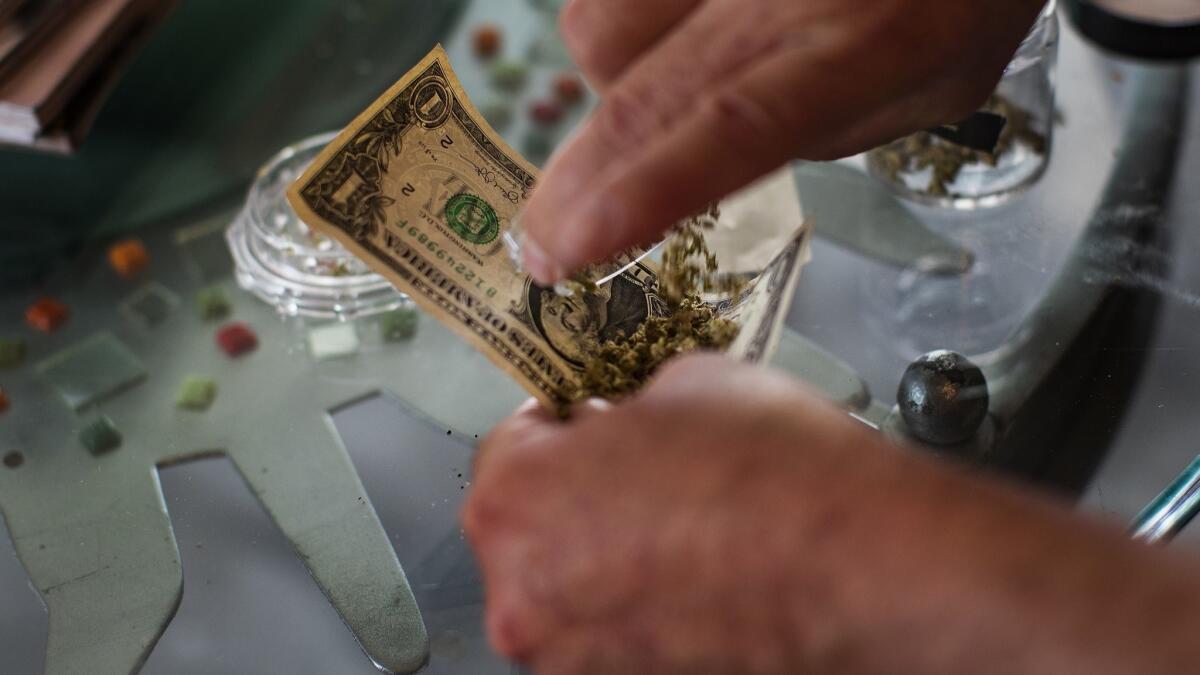 Innkeeper John Thatcher uses a dollar bill to roll a joint at his pot-friendly Desert Hot Springs Inn.