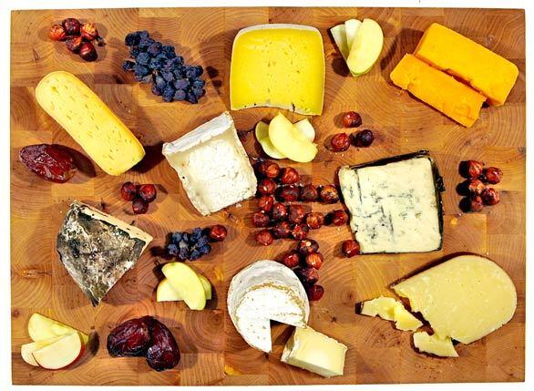 The cheeses shown are, clockwise from the 6 o'clock position, Jasper Hill Farm's Constant Bliss cow's milk cheese, Sally Jackson sheep's milk (white cheese wrapped with chestnut leaves), Grayson washed-rind (yellow cheese with orange rind), and Truffle Tremor goat's milk (white cheese with milky white rind), Trailhead cow's milk, Hook's Cheddar, Rogue River Blue and Vella Dry Jack.