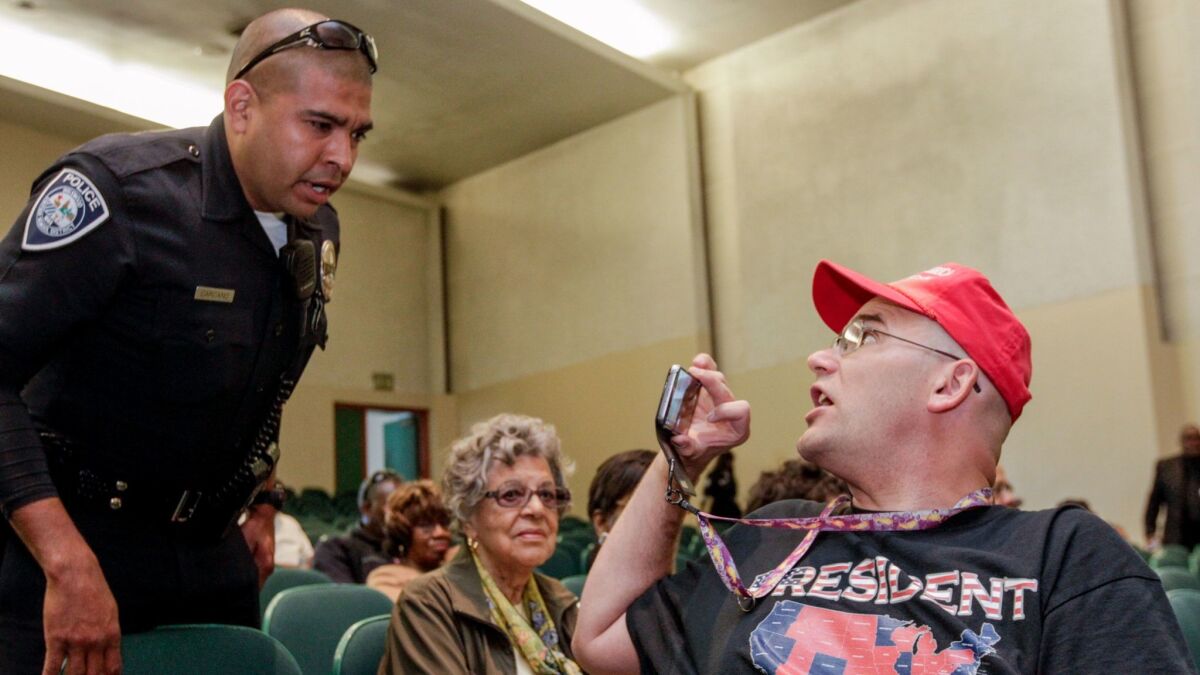 An Inglewood police officer talks to outspoken conservative activist Arthur Schaper at a town hall meeting held by Maxine Waters in May.