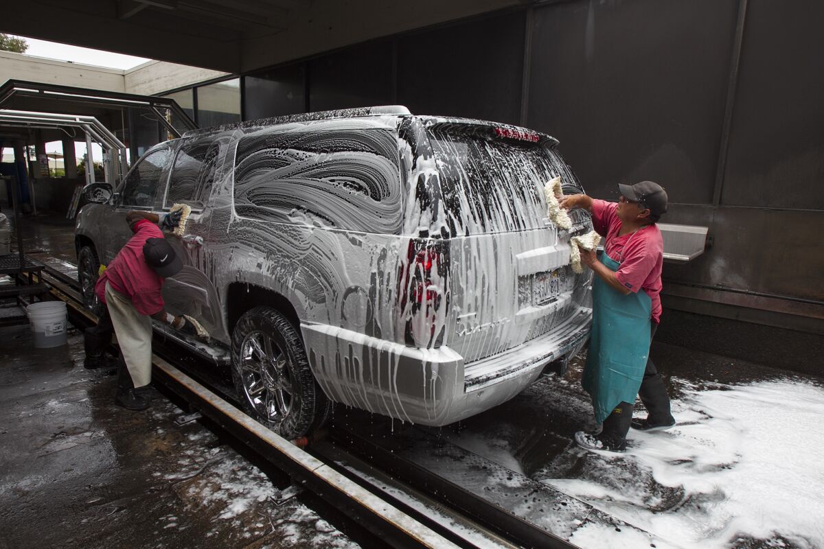 Employees hand-wash a car at Newport Beach Car Wash. Using a car wash instead of doing it yourself can help save water.