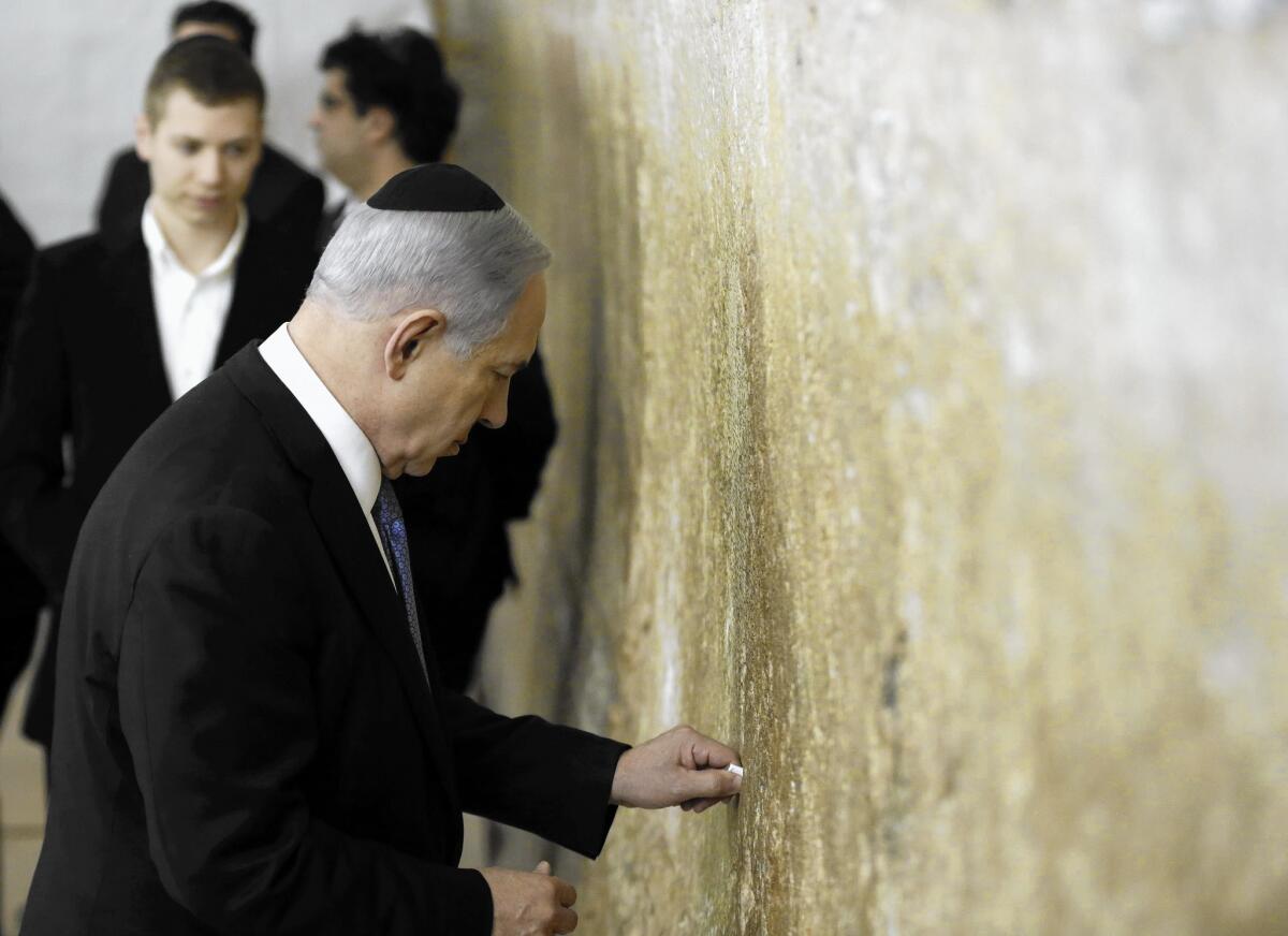 Israeli Prime Minister Benjamin Netanyahu places a note into the Western Wall in Jerusalem after his party's victory.
