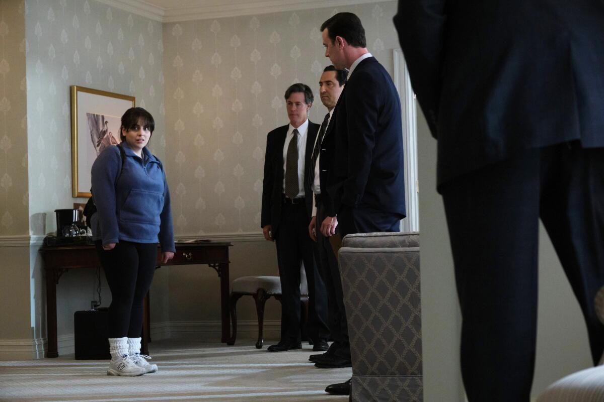 A young woman surrounded by federal agents in a hotel room