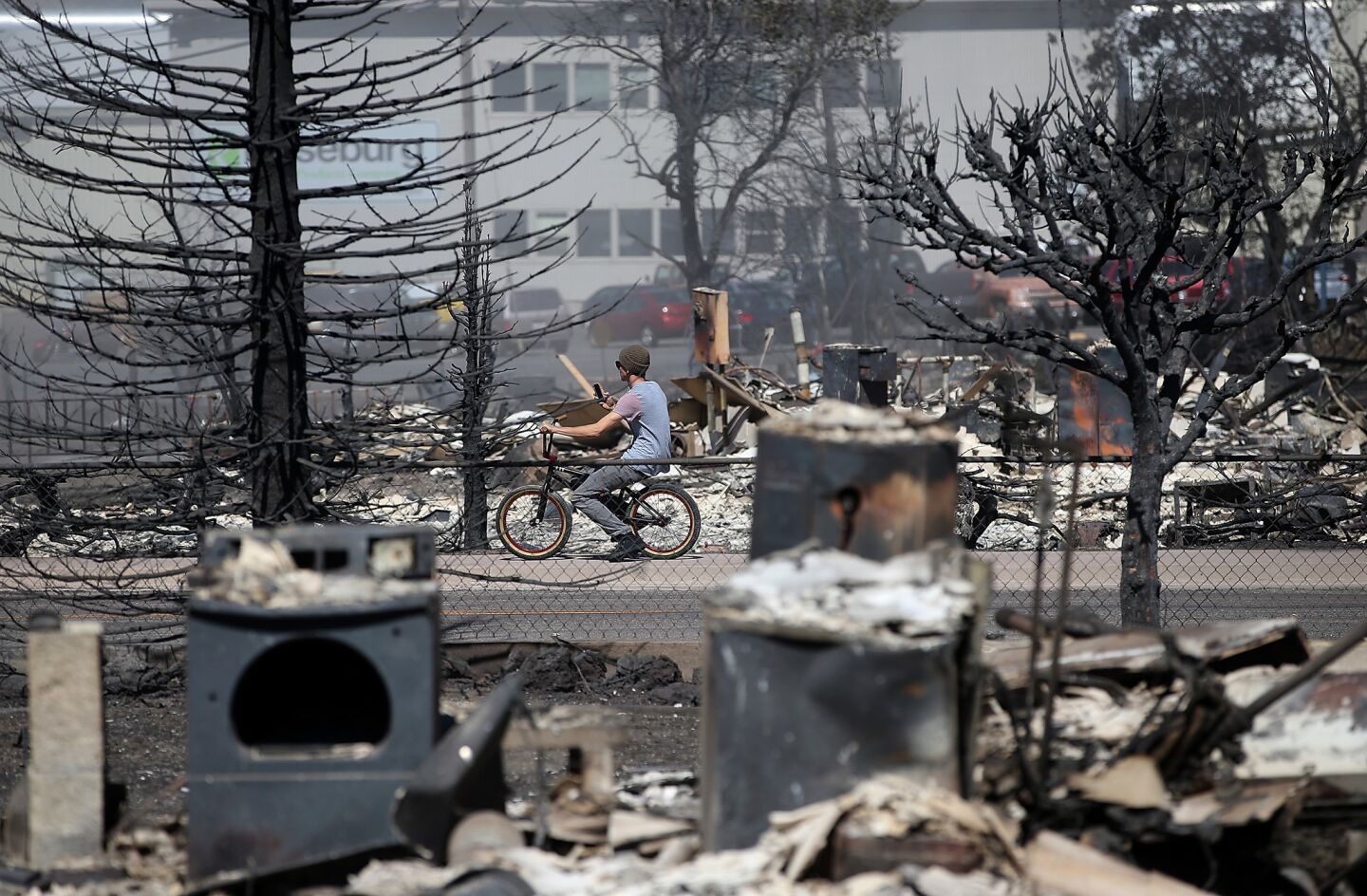 A cyclist stops to take a picture of the remains of destroyed homes in Weed, Calif.