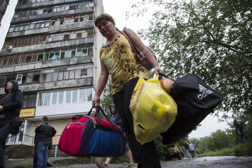Residents of eastern Ukraine continued to evacuate Tuesday from cities targeted for recovery by government forces, including this woman leaving her home in Luhansk.